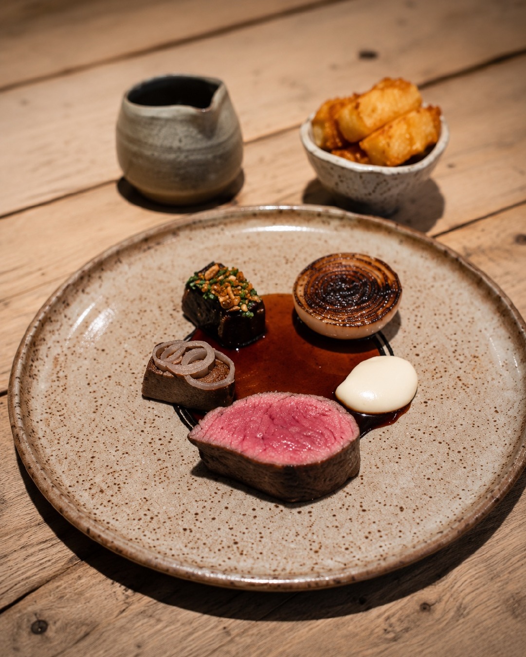A composed beef dish with carrot, spring onion and sauce.